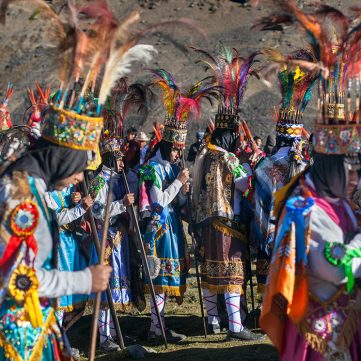Comparsa de danzantes de vistiendo trajes coloridos y tocados de plumas, en la procesión del señor de Qoyllur Riti.
