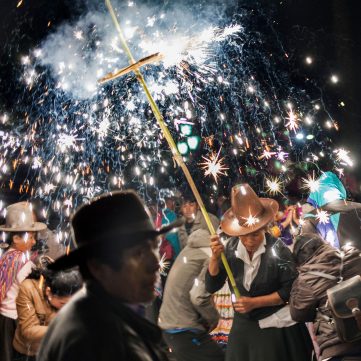 Celebración nocturan dedicada a Mamá Mecha, patrona de Carhuaz. Personas observan los fuegos artificiales que desprenden chispas brillantes cerca a la multitud.